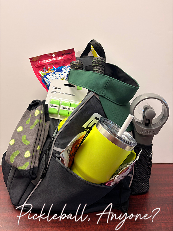Pickleball themed raffle basket with pickle socks, water bottle, racquets and overgrips, visor and handheld fan