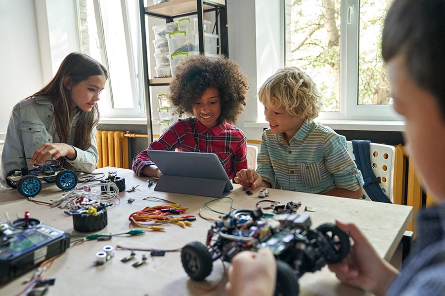 Group of children seated around classroom table engaging in STEM learning activity