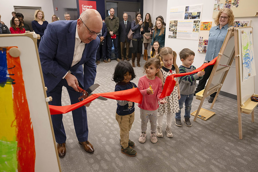 CMU President Farnam Jahanian and four children from the Cyert Center cutting a ribbon at the entrance of the new Cyert space