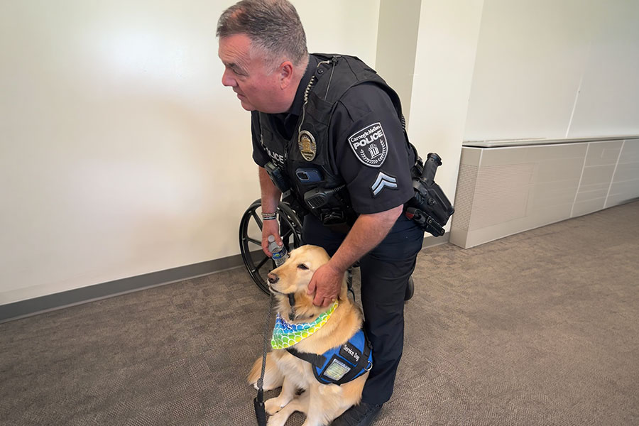 CMU police officer petting golden retriever service dog