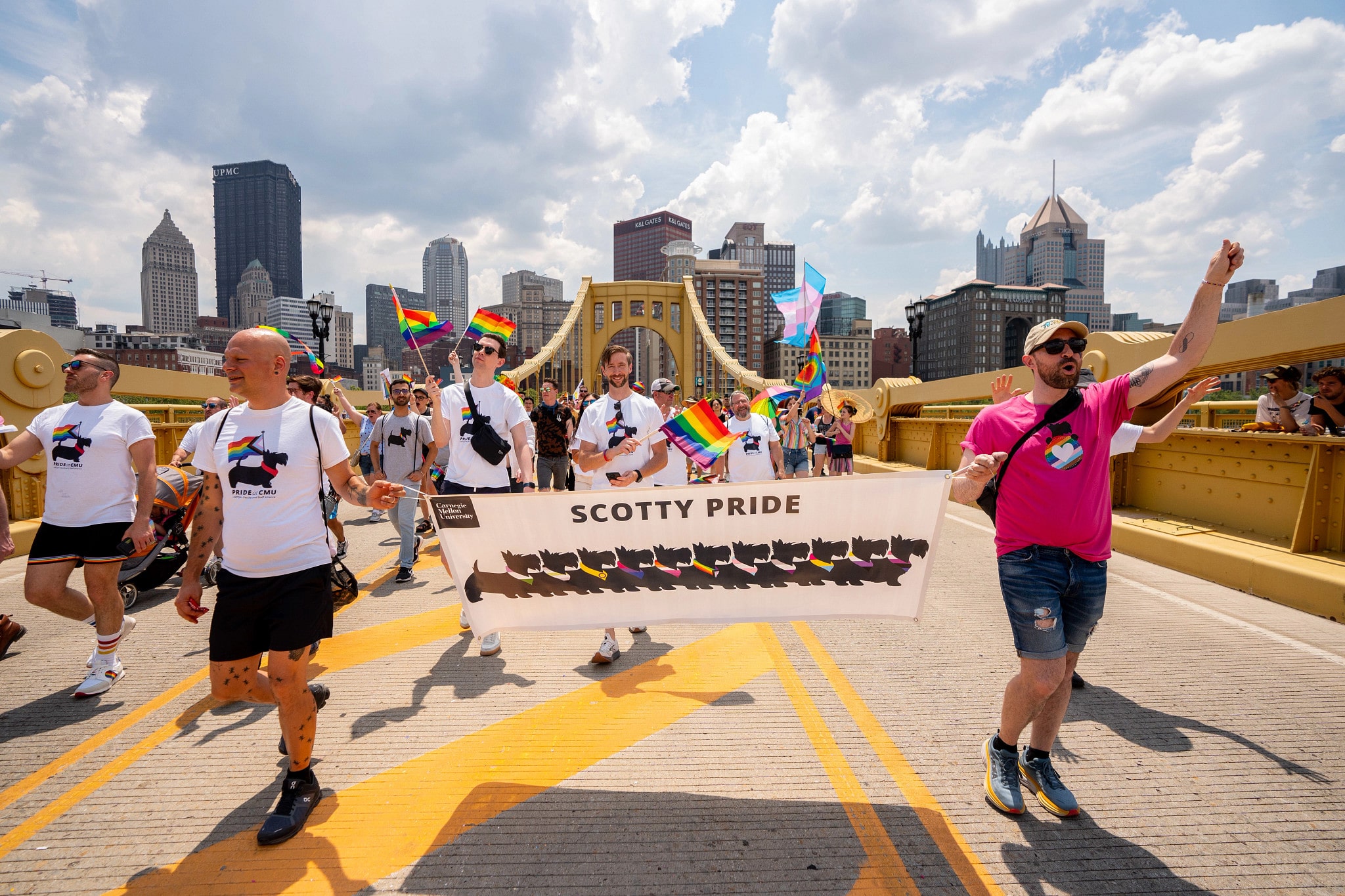 CMU participants marching across bridge carrying Scotty Pride banner