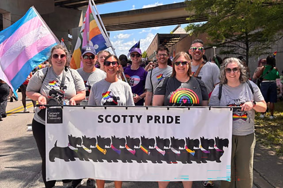 LGBTQIA+ Alliance members posing on parade route behind Scotty Pride banner