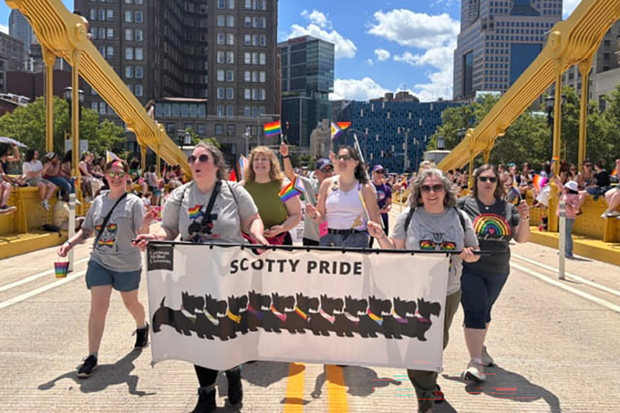 LGBTQIA+ Alliance members posing on parade route behind Scotty Pride banner