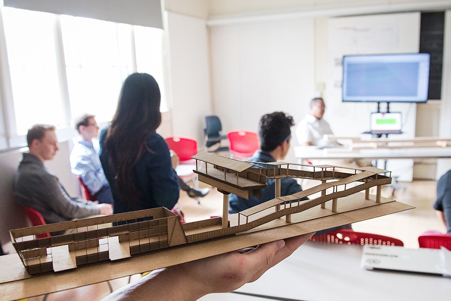 students in an architecture class, a model bridge in the foreground.