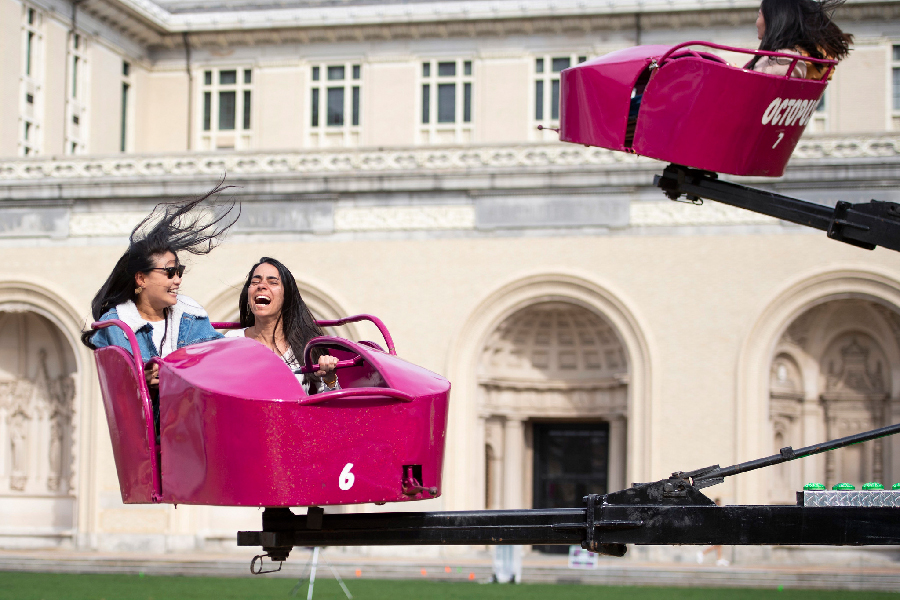 Two women riding in a carnival ride on the campus Cut during Spring Carnival