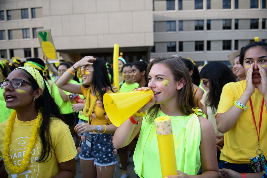 Students participating in an orientation event in yellow shirts with megaphones