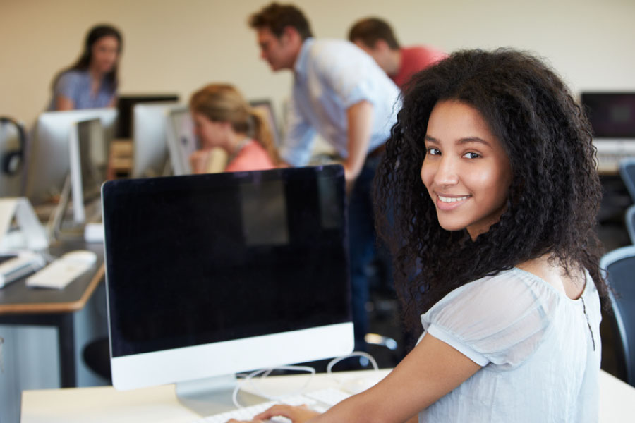 Female student smiling and looking at computer screen with new SIO homepage
