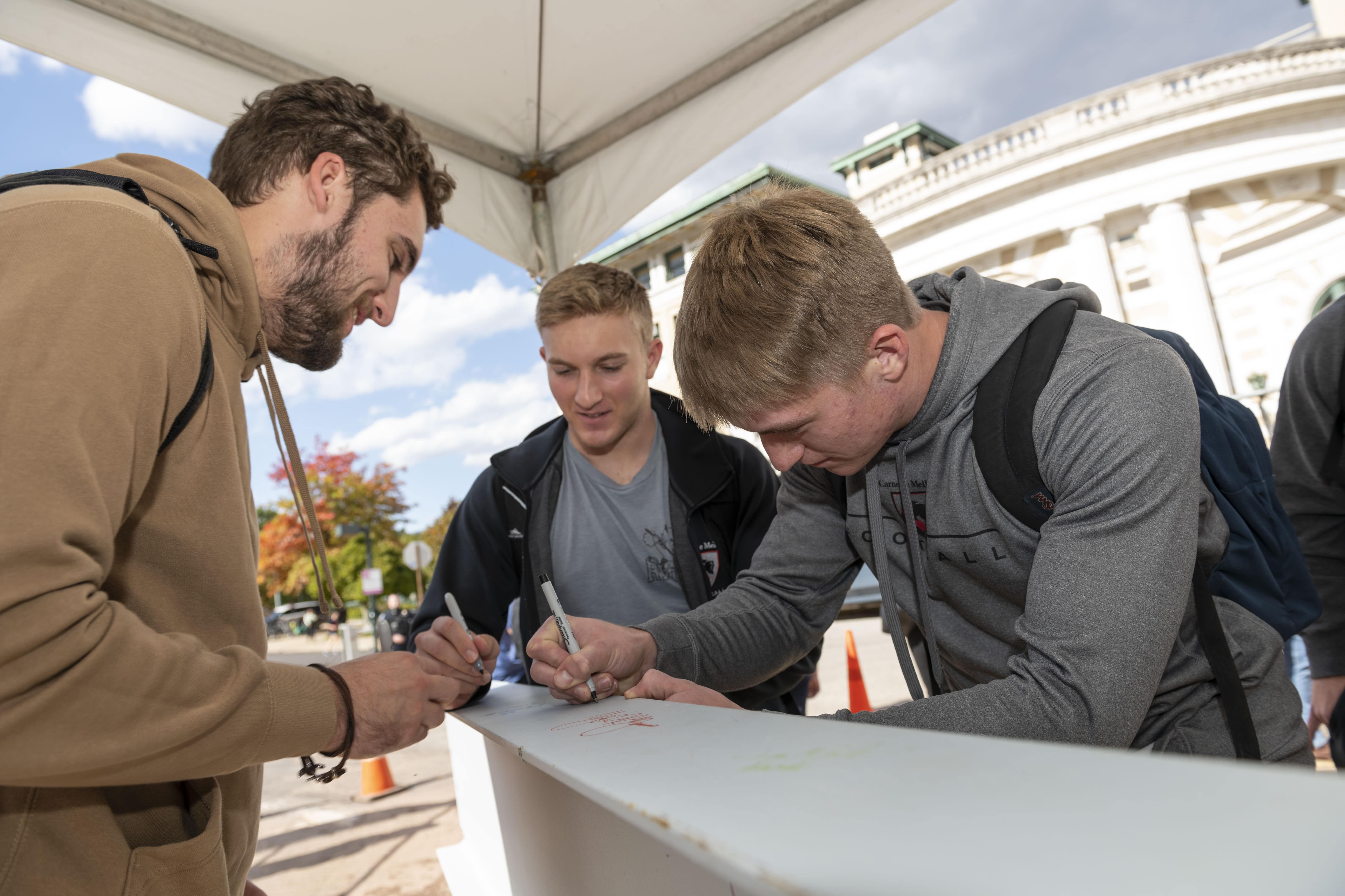 Community members sign the beam