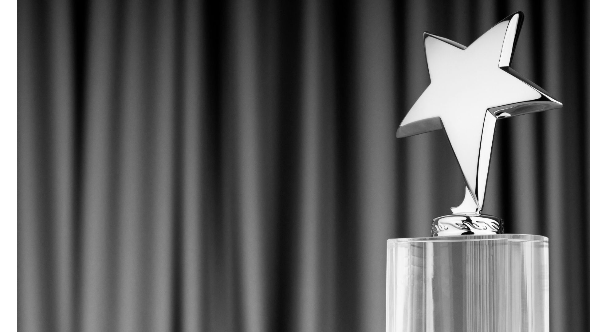 a silver trophy in the shape of a star is in front of a gray curtain backdrop