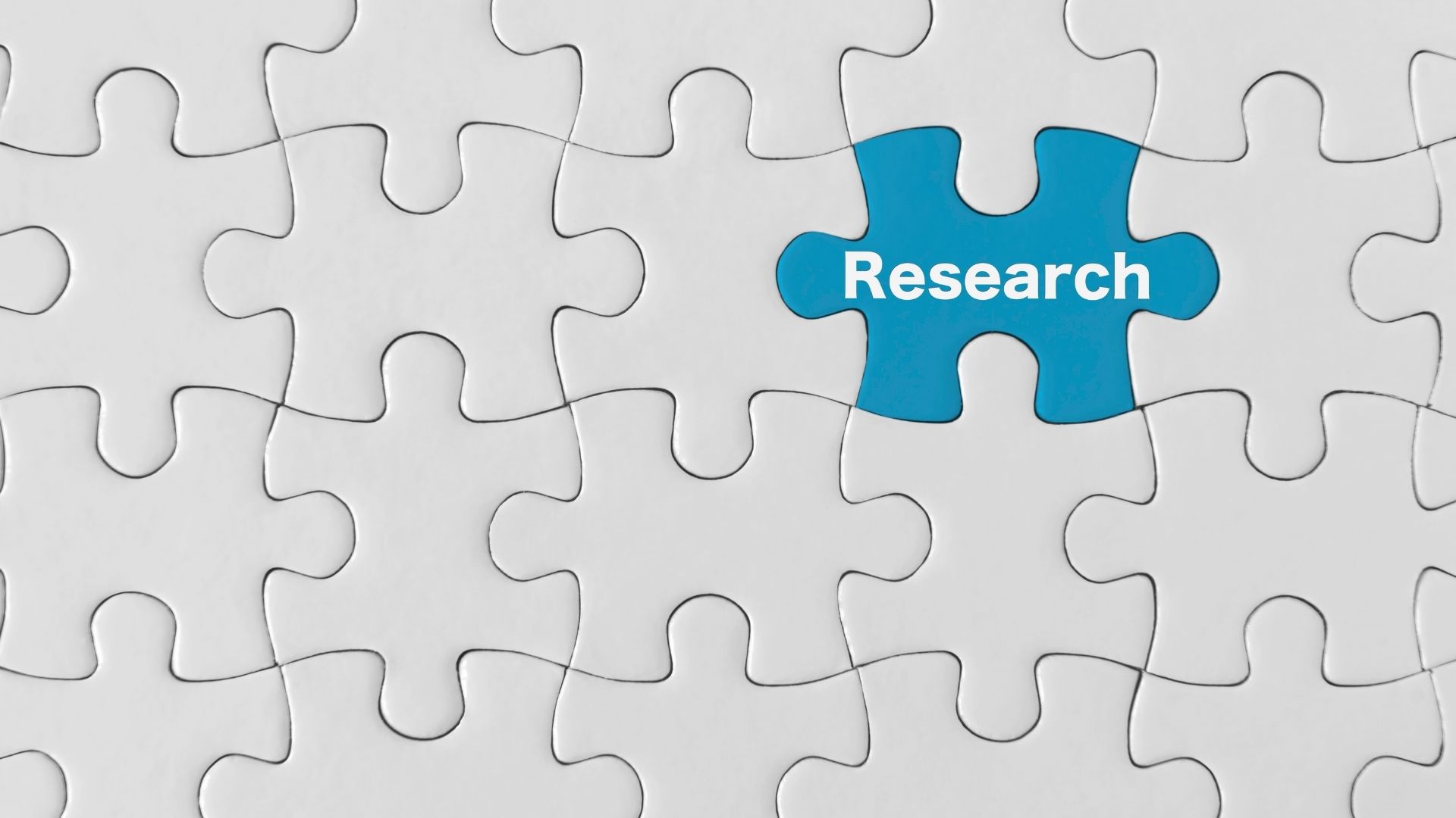 white puzzle pieces interlock, among them is one blue puzzle piece with the word research on it