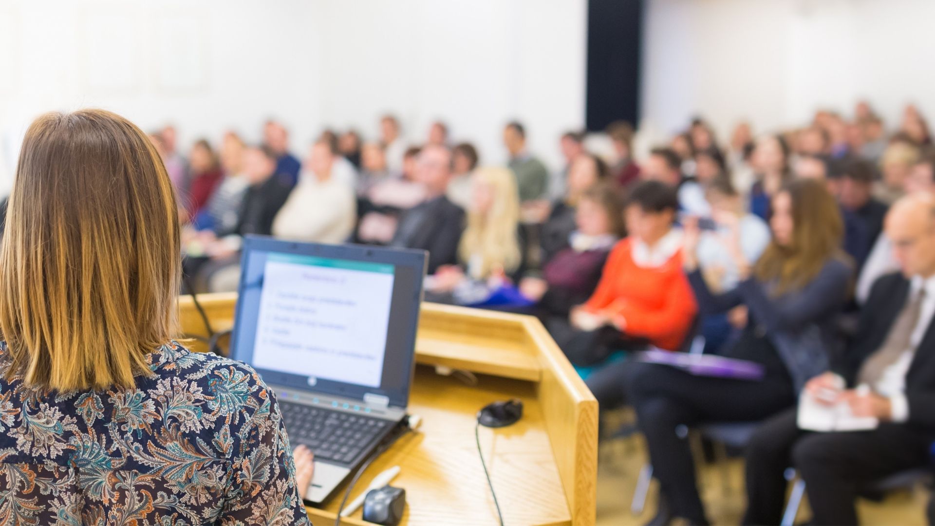 a speaker presents to a room of attendees