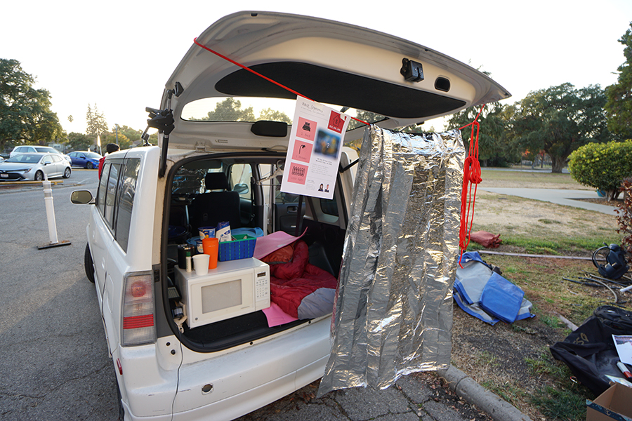 In one example , a car is set up with a sleeping bag, portable shower, and microwave