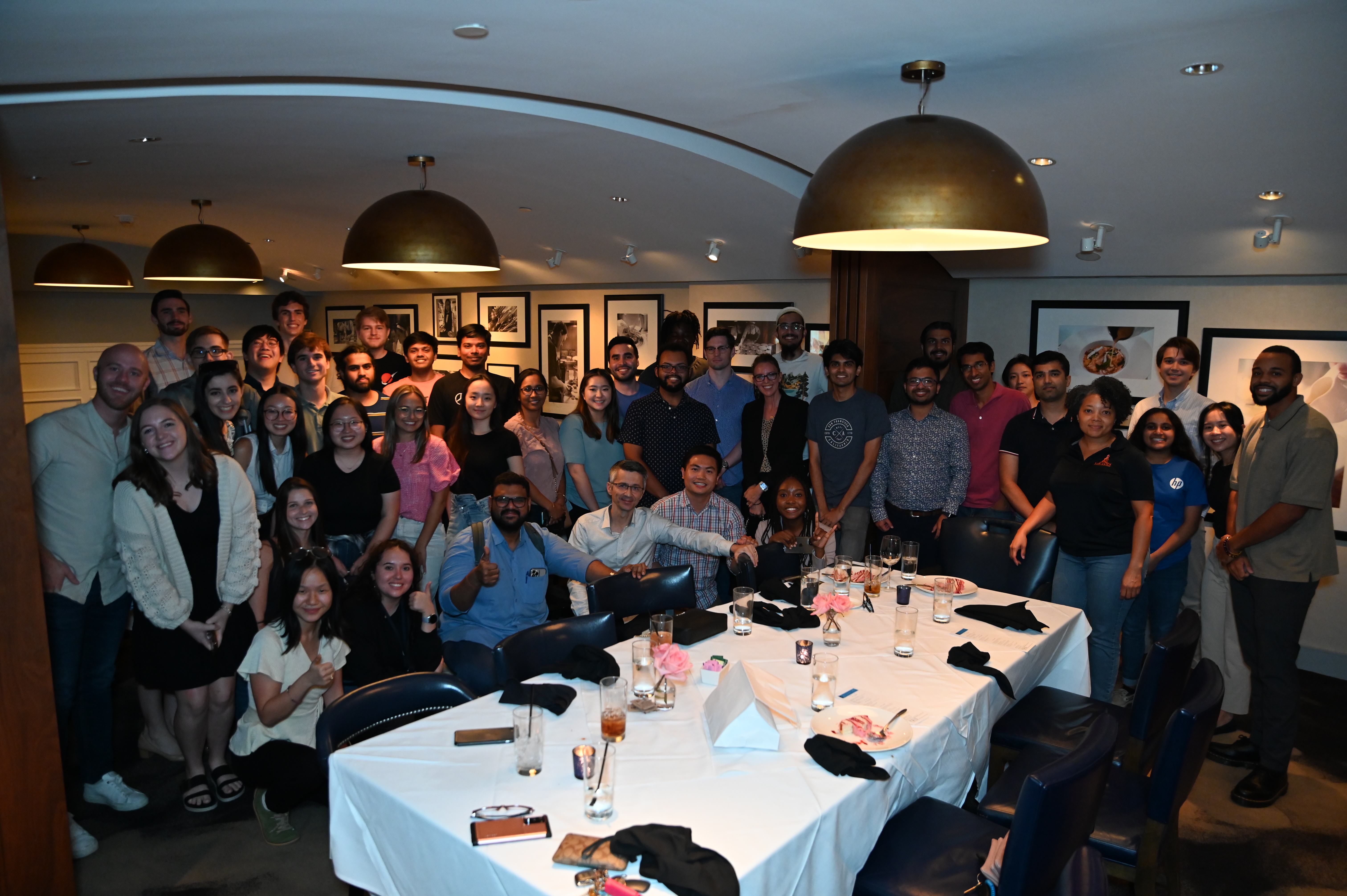 student abhishek iyer stands with fellow interns around a dining table at an HP company event for a photograph