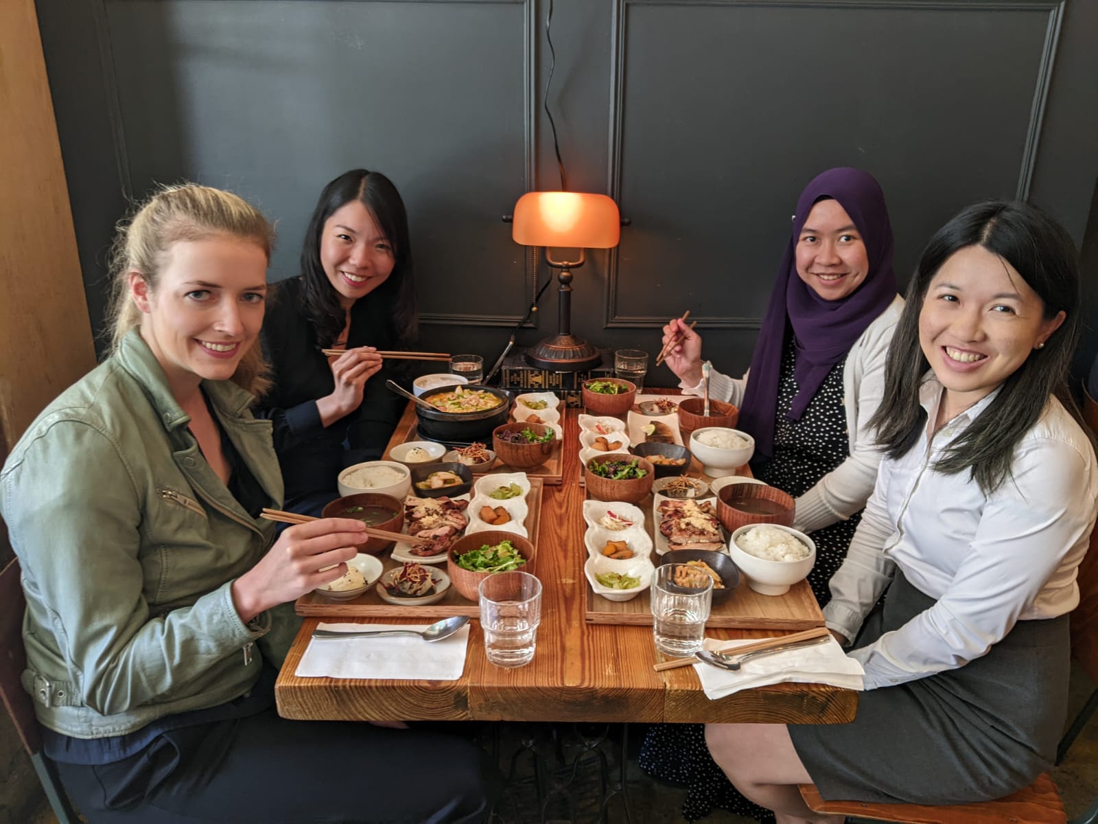 student aisya aziz is photographed sitting at a table with fellow Barnes & Noble Education interns