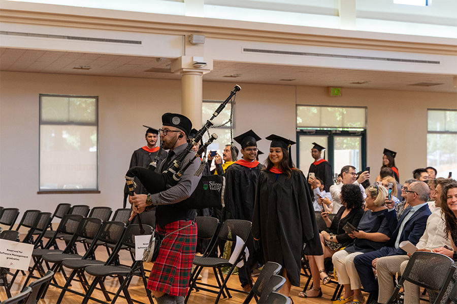 a bagpiper leads students into the Diploma Cremony