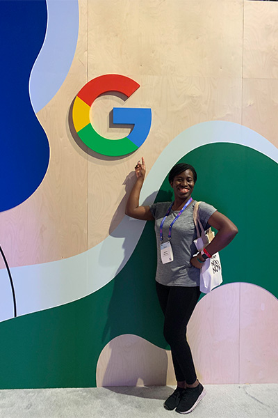 Jessica poses outside of the Google booth in the Expo Hall
