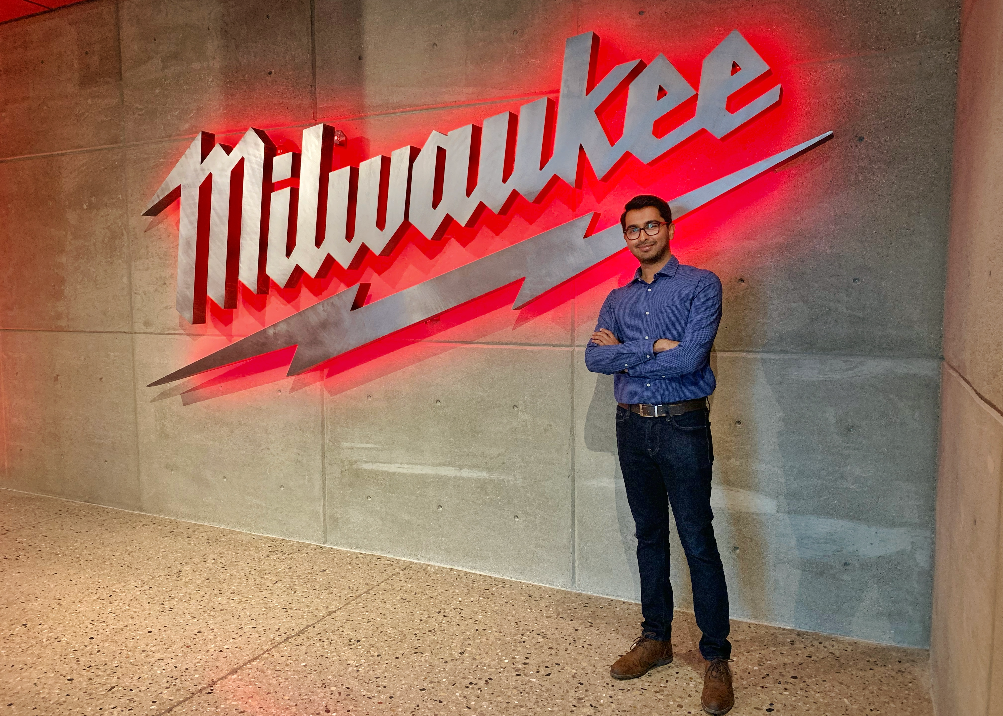 student manas mahaddalkar stands in front of the Milwaukee Tool logo