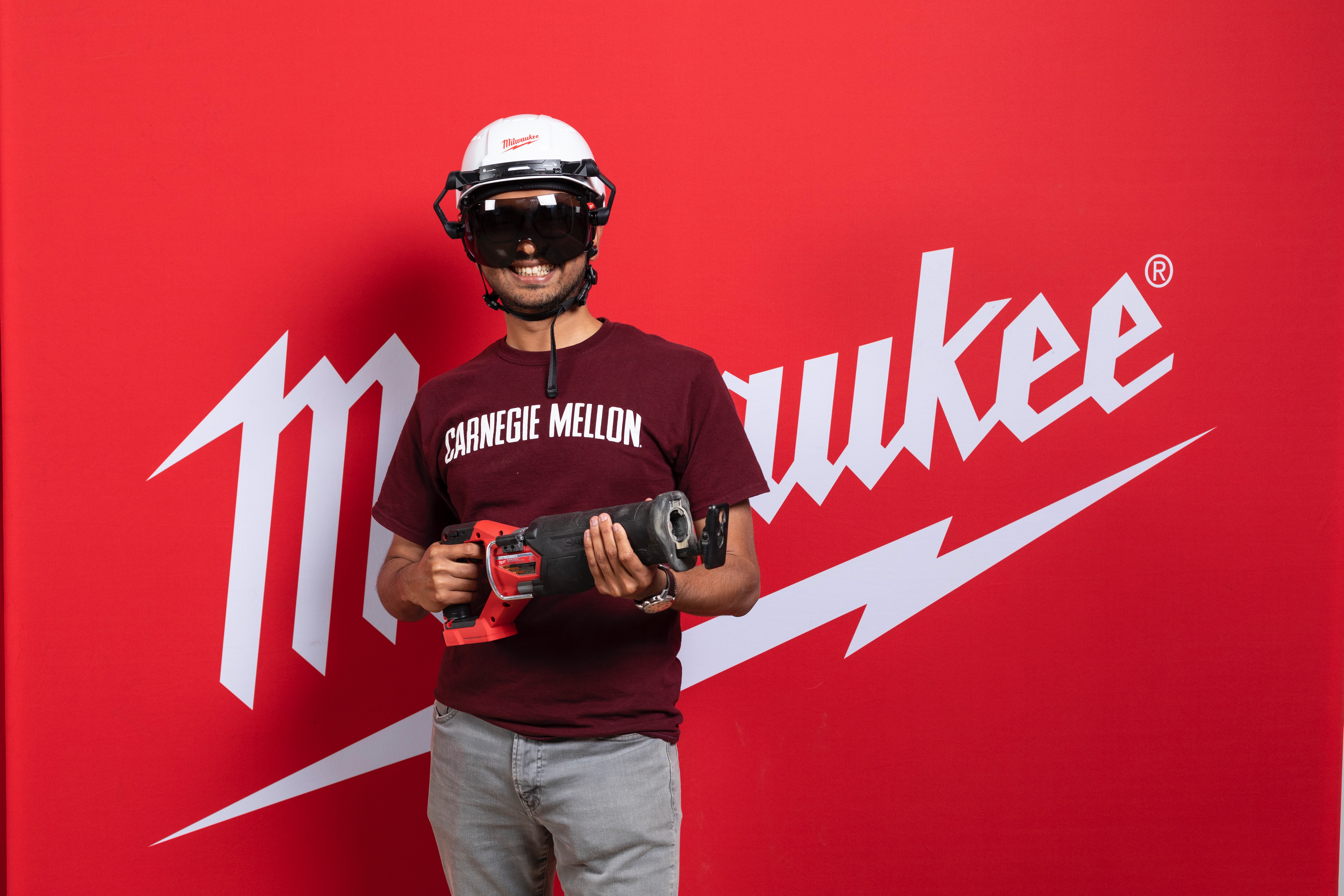 student manas mahaddalkar poses with a power tool in front of a red Milwaukee Tool banner