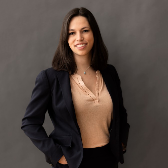 a brunette woman with a black jacket poses for a photo.