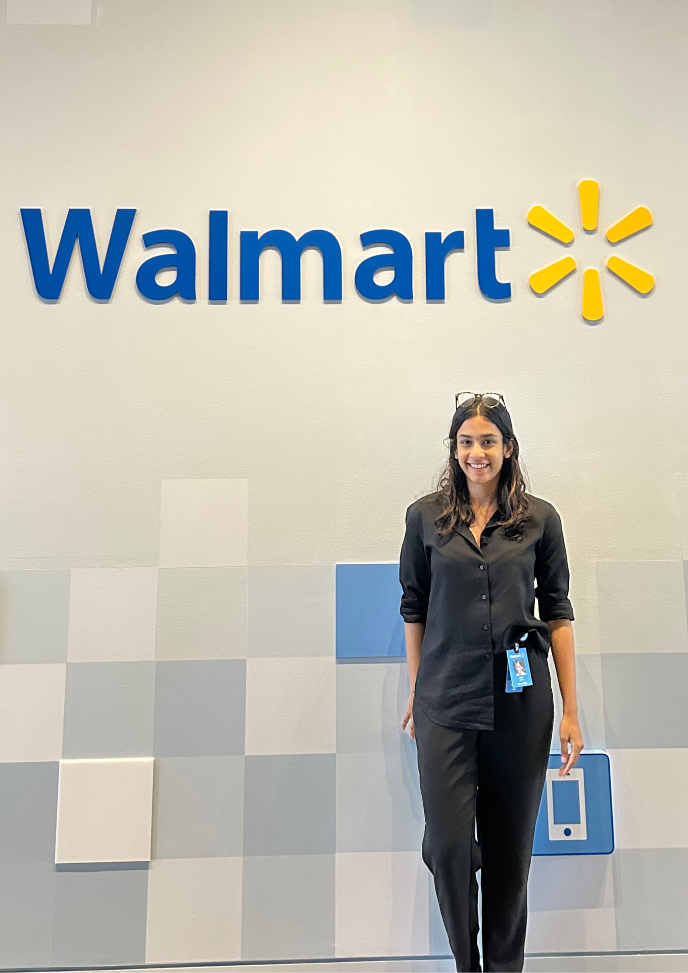 A girl with a black shirt stands in front of a Walmart sign. 