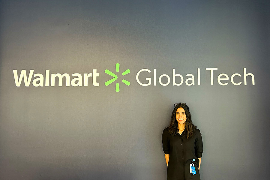 Myria poses with a Walmart Global Tech sign at her internship