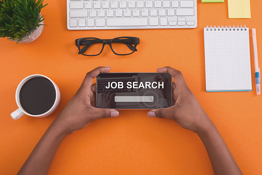 photo of an orange background with a smart phone screen that reads "job search"
