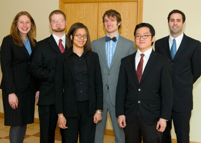 The six team members pose standing in their business attire.