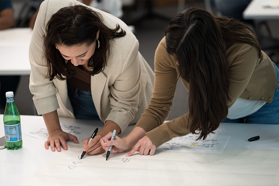 Students collaborate on a design project, each drawing a different sketch on a poster