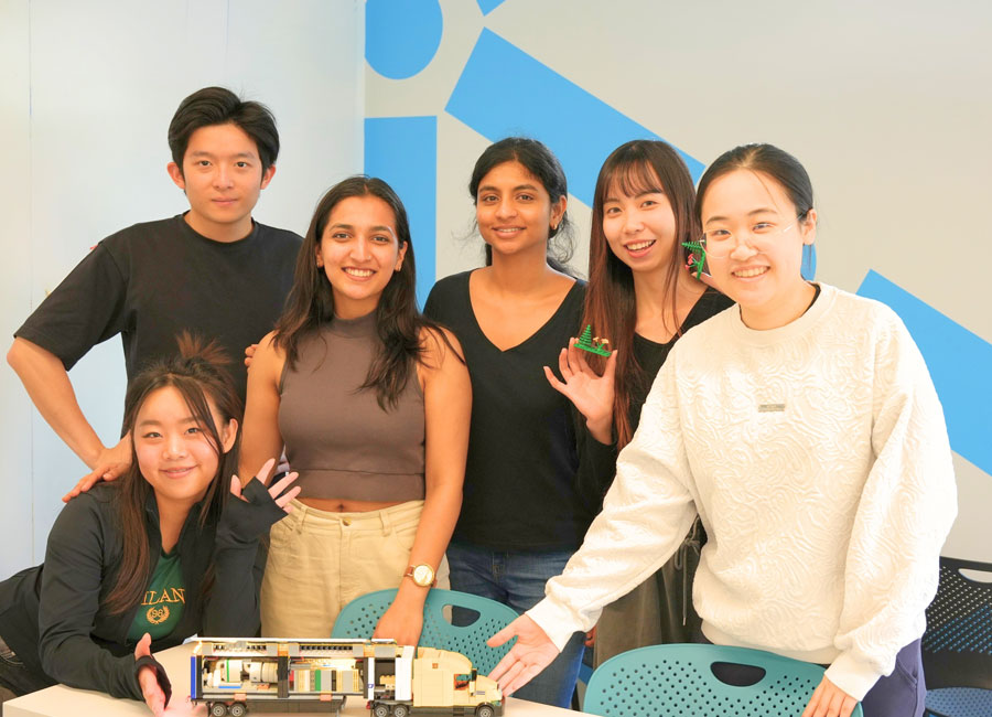 innovation design masters student pose with a lego version of their prototype