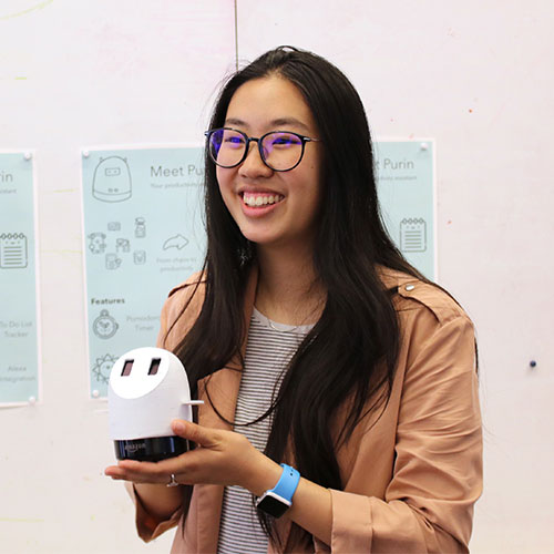 female student holding a product during a presentation