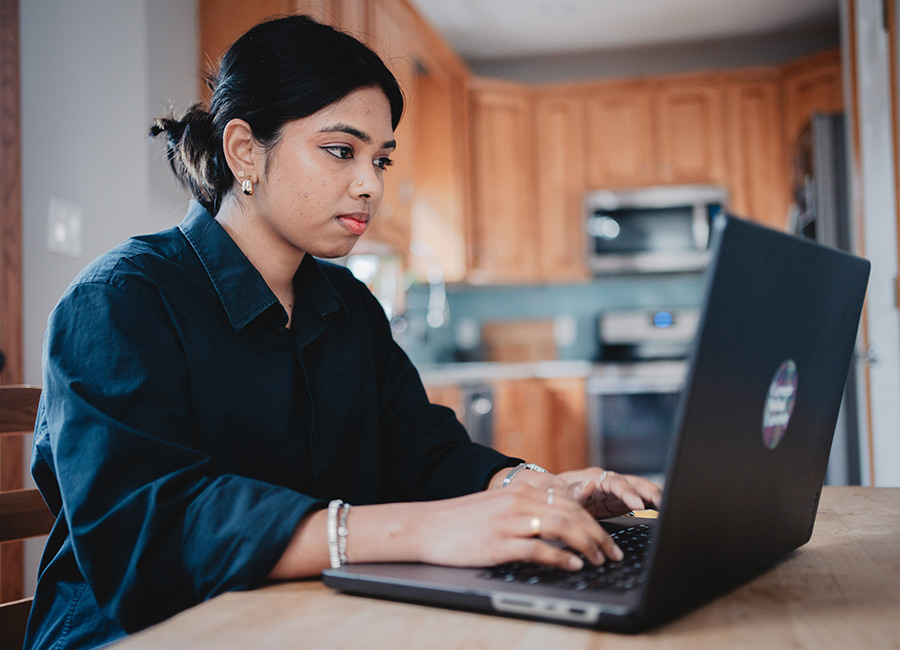 image of a female student working on her laptop in a common area completing work for an online innovation certificate