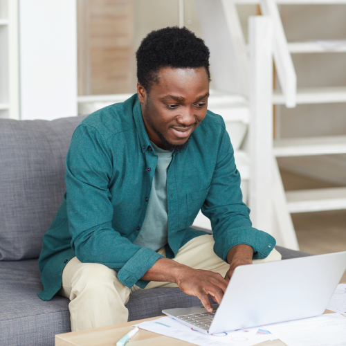 guy sitting on a couch typing on a laptop