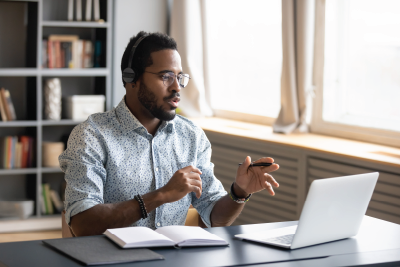 man talking to people on a laptop and working at the desk
