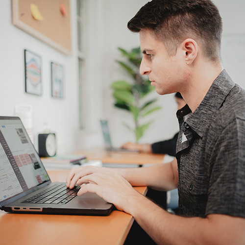 male student working on an assignment at his computer, learn innovation