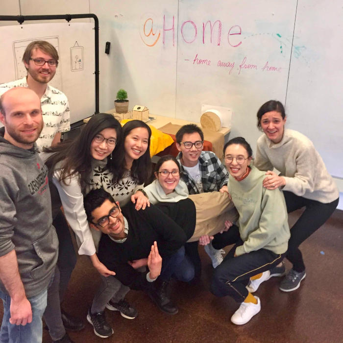 A group of students take a break from working on their Internet of Things project to smile for the camera in front of a whiteboard.