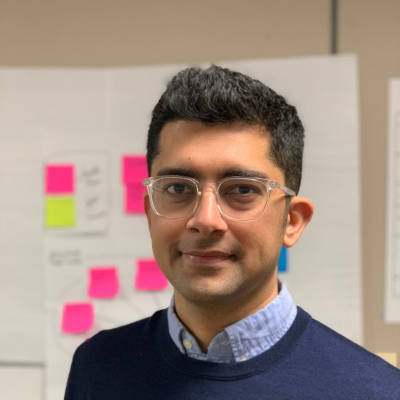 Manchit Rajani poses in front of a white board with sticky notes