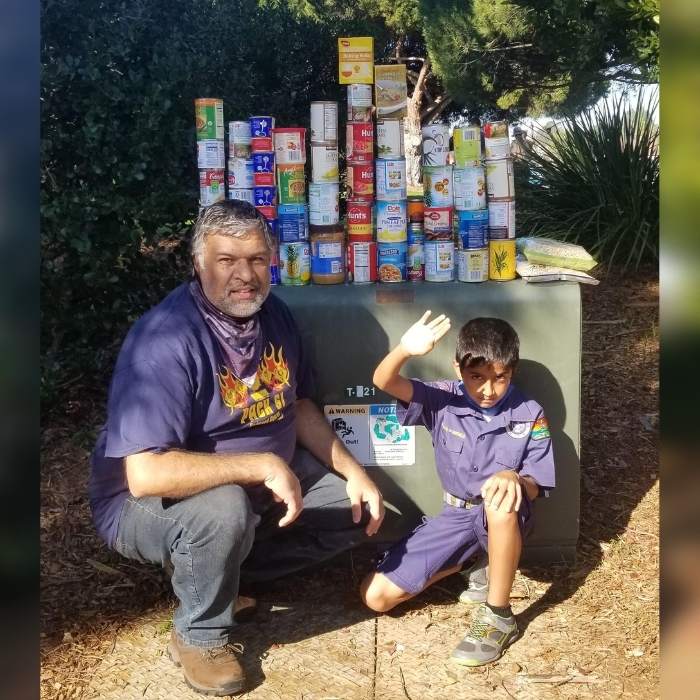 Suterwala poses with cub scout around food drive donations