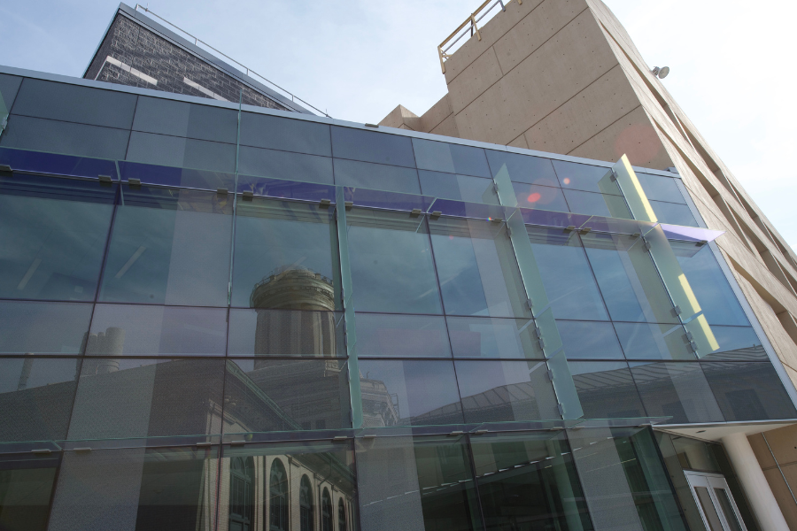 The glass front of a building on campus with the image of another building being reflected on it