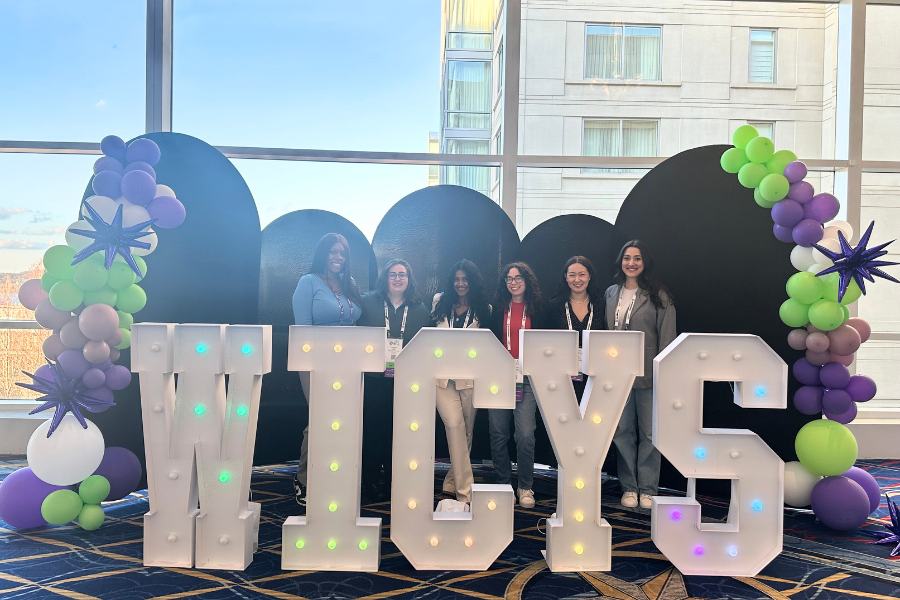 A group of current students and alumni posing for a picture at the WiCyS conference