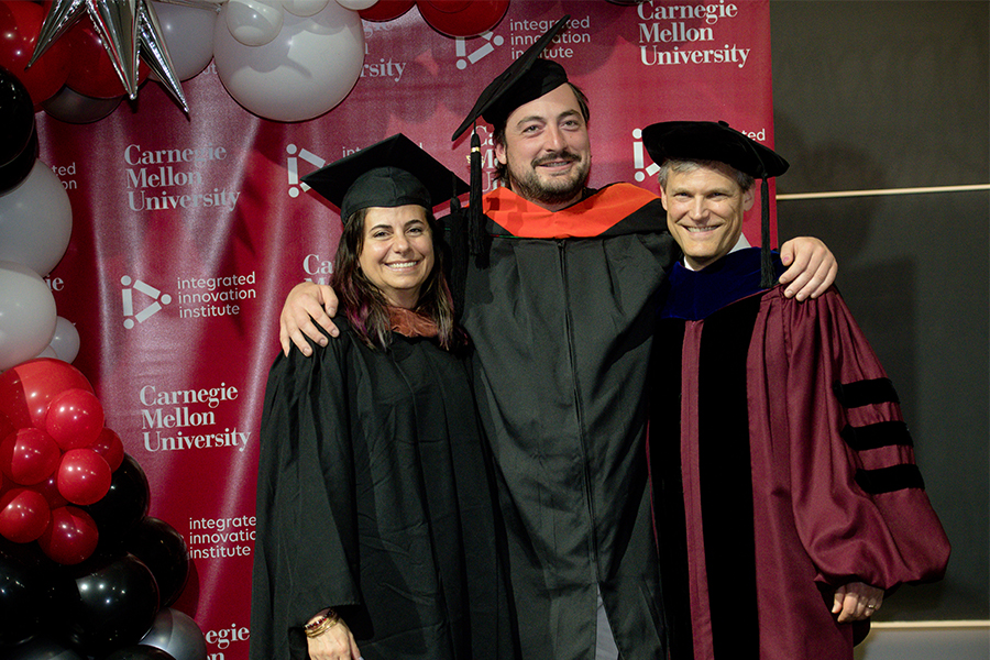 student standing with professors