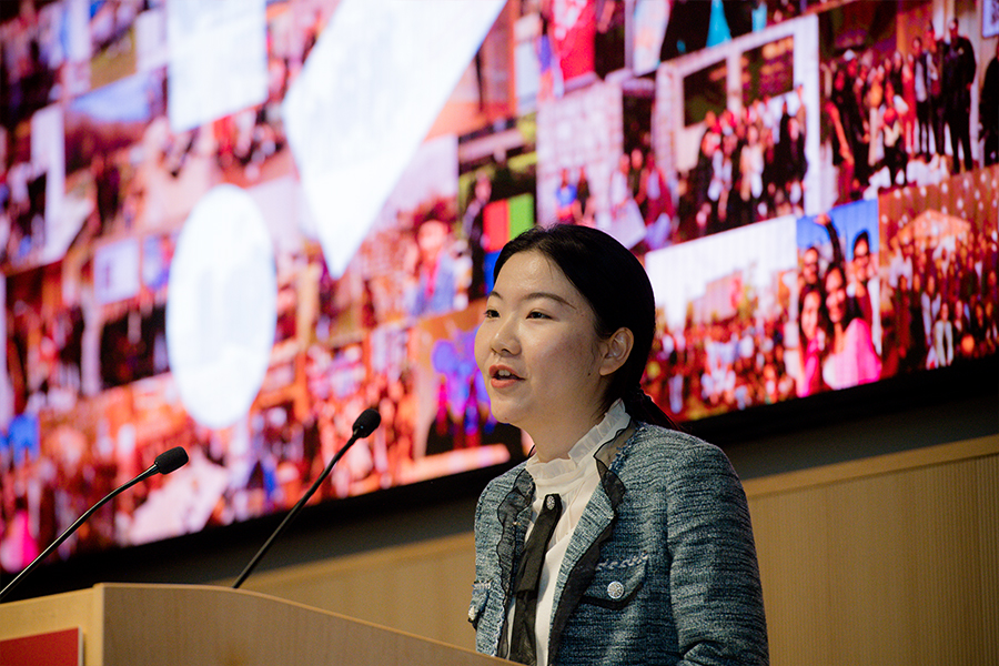 Shixian stands at a podium and speaks to the audience