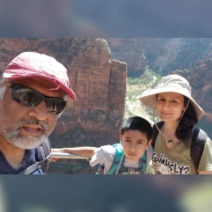 Suterwala, his wife, and son on a hiking trip with rocky mountains behind them