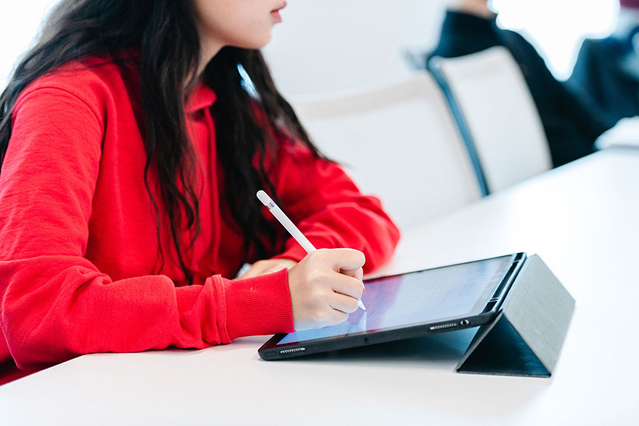 woman in classroom writing on tablet