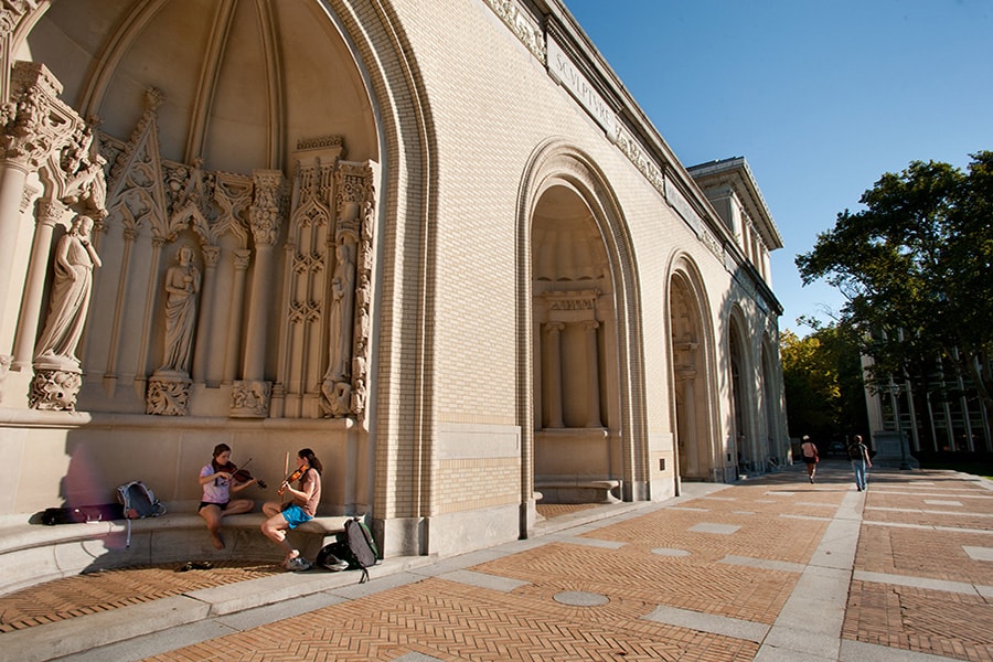 Two students playing violin outside of the College of Fine Arts