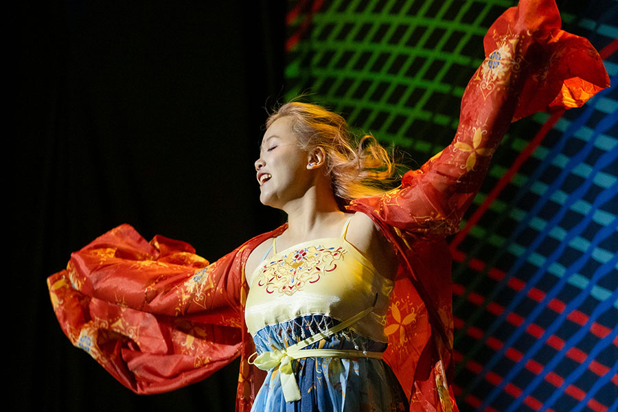 Young woman performing a dance in front of a CMU tartan backdrop