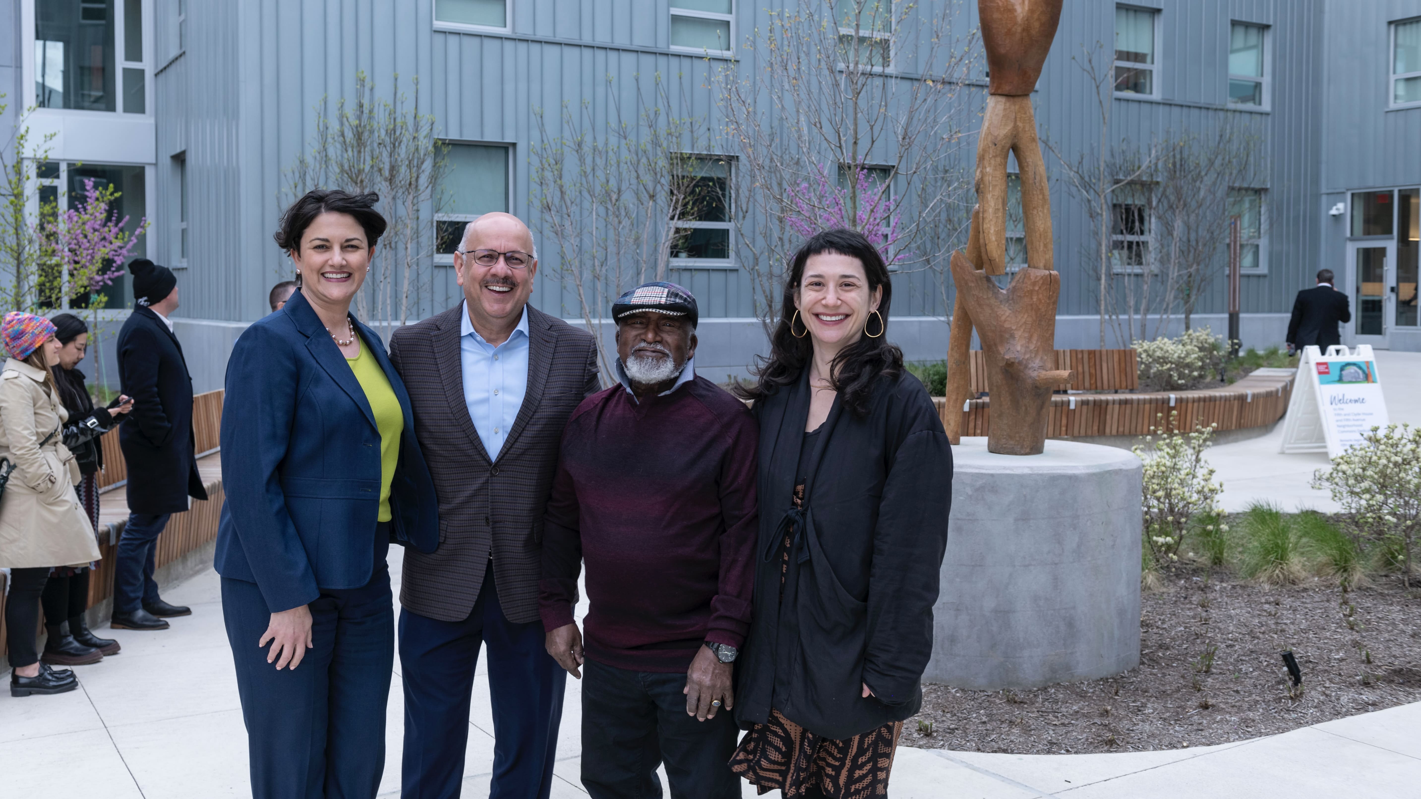 Farnam Jahanian and a group of CMU leaders stand in front of a public art sculpture outside the new Fifth and Clyde Residence Hall on CMU's campus