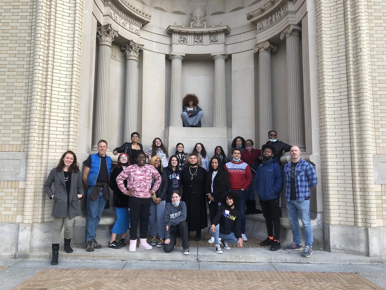 LEAP students and their teachers posing in a carved stone niche in front of the College of Fine Arts.