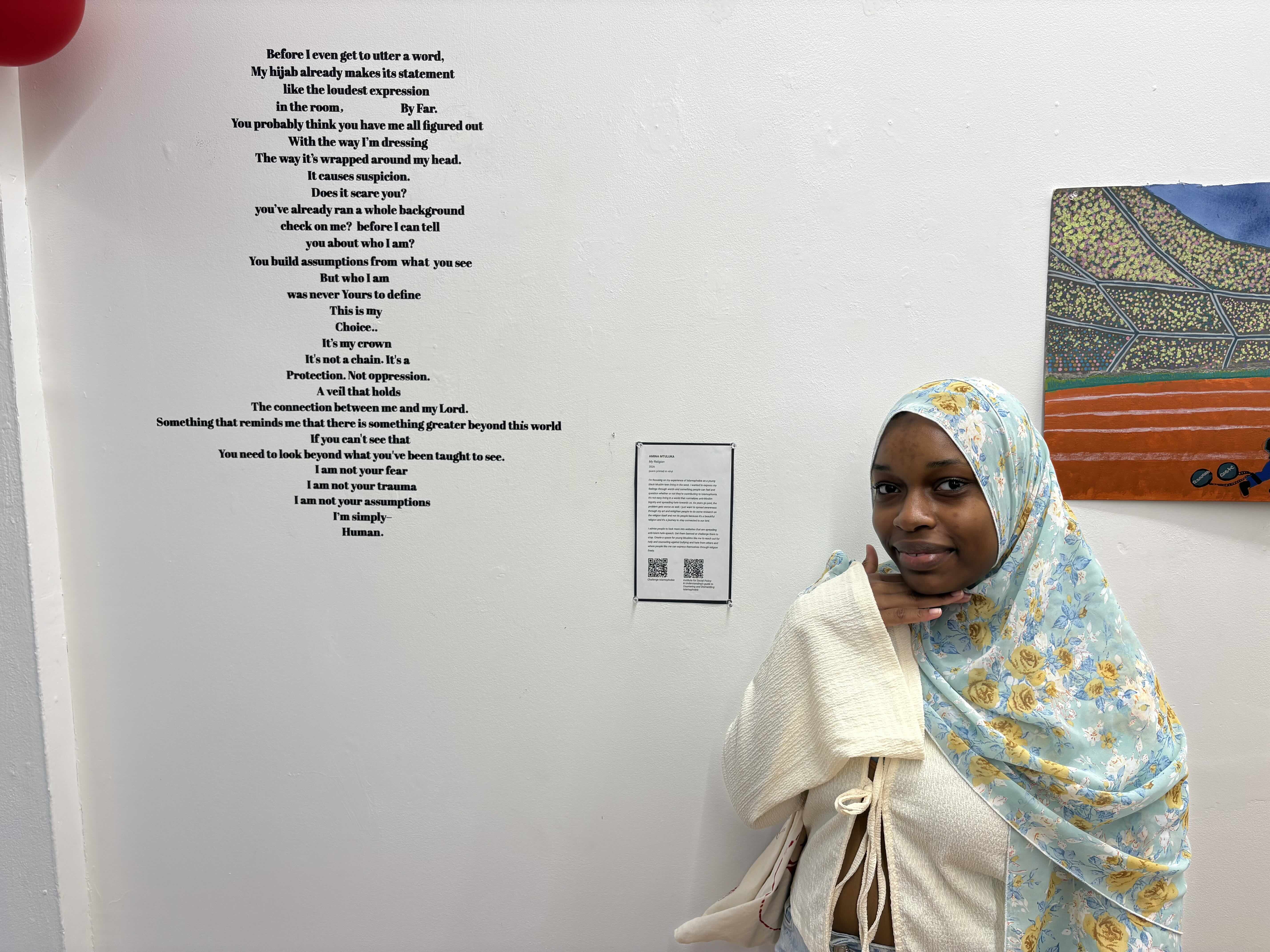 Student standing next to poem that was cut in vinyl and mounted to gallery wall.