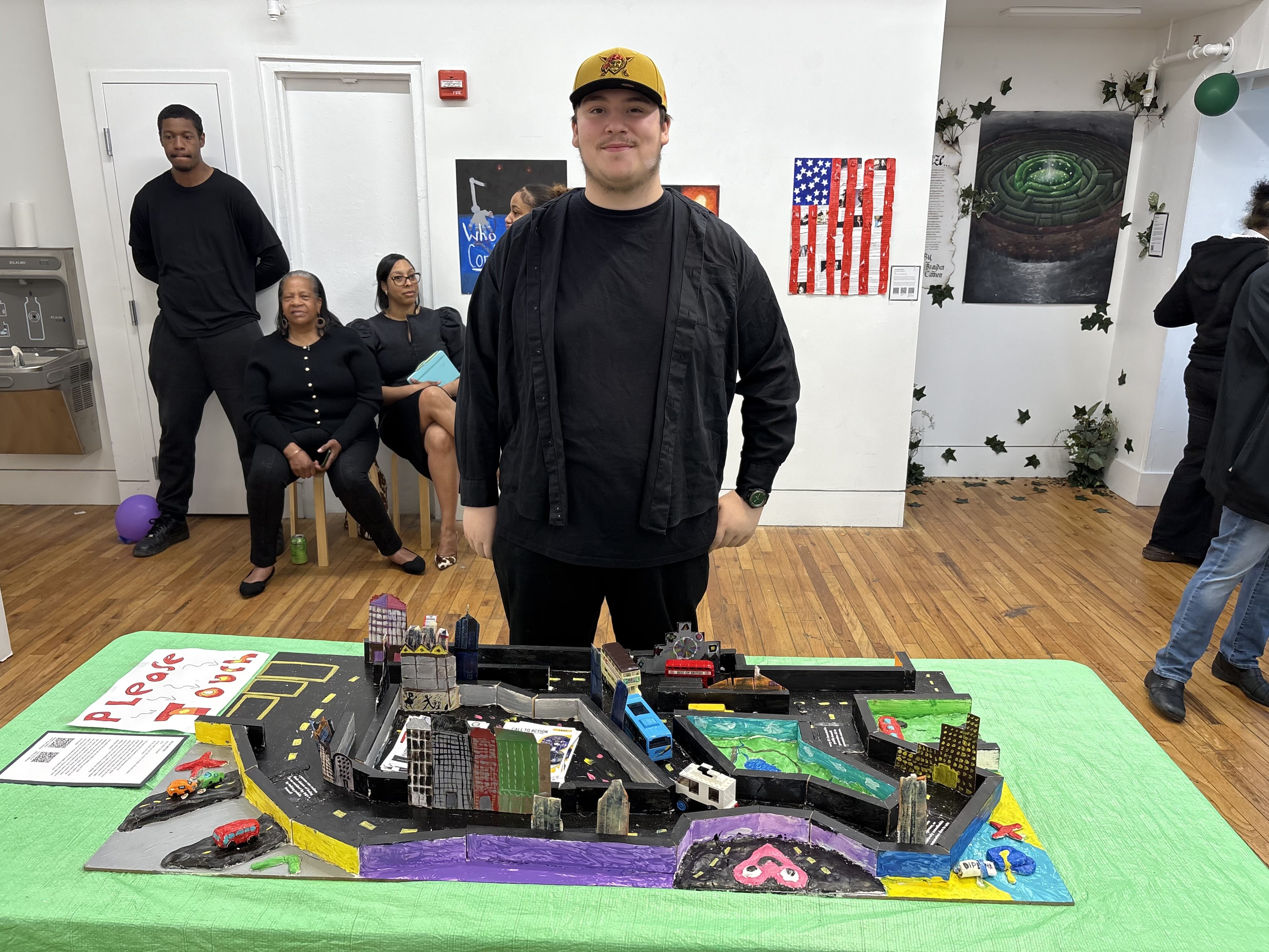 Student standing behind a table with a colorful board game on top of it.