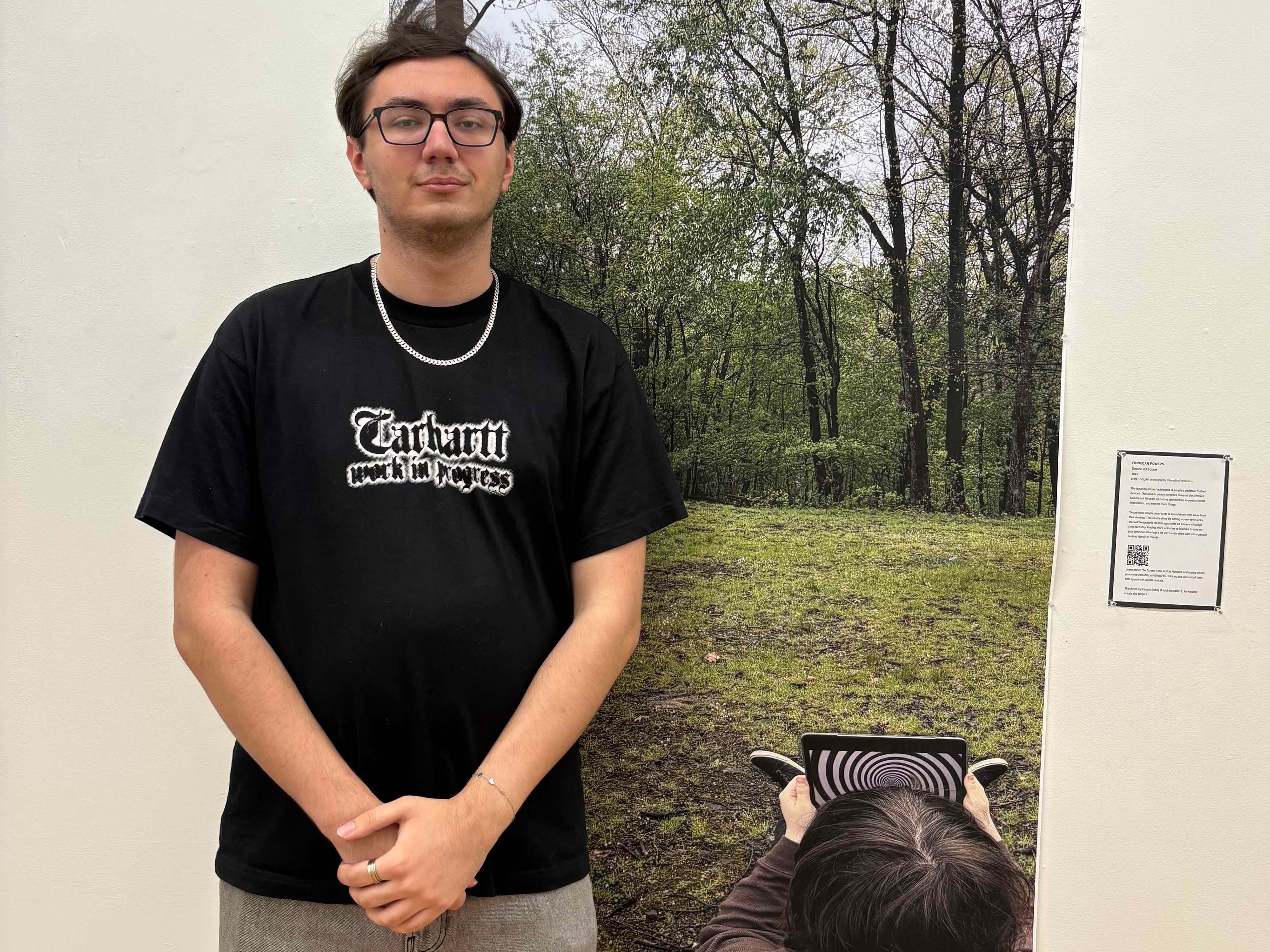 Student standing in front of a very large poster.